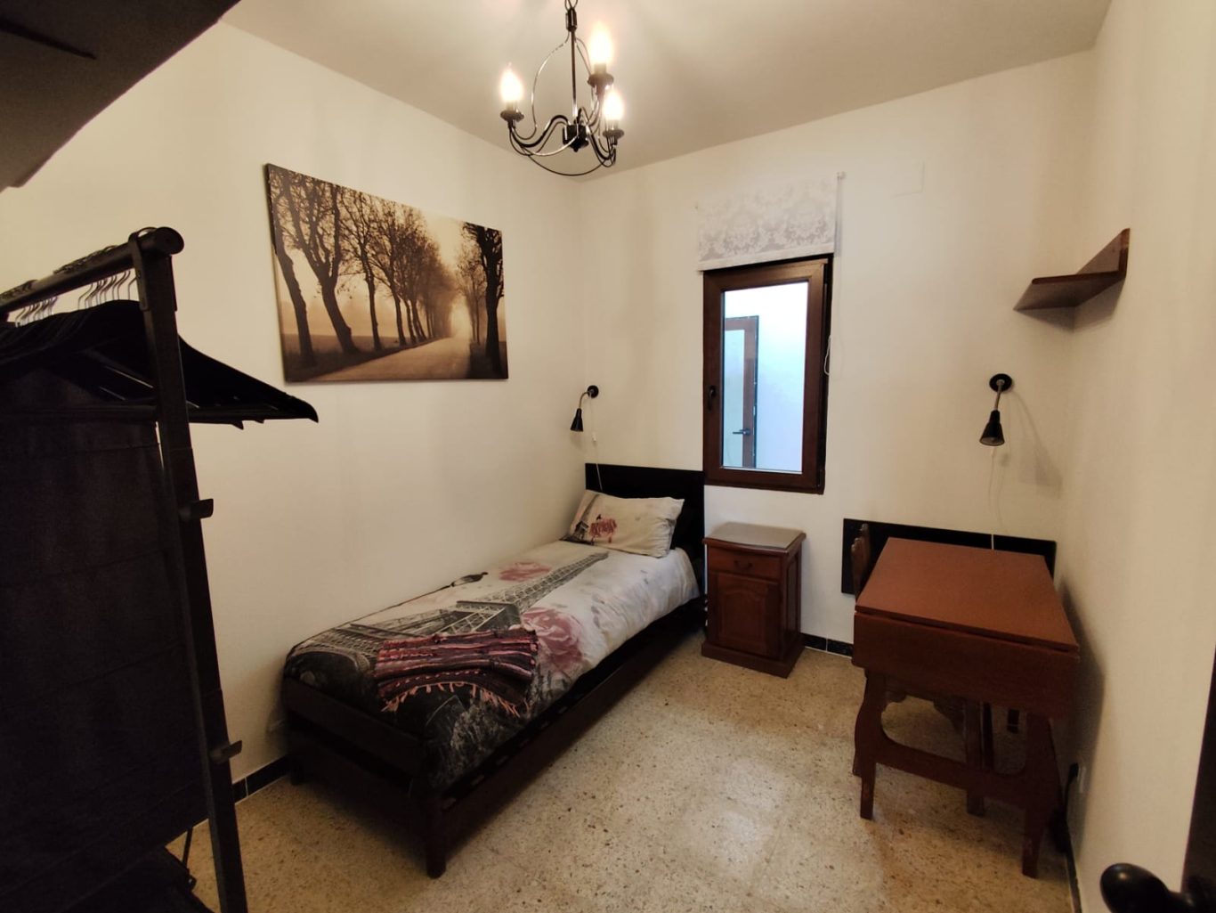 Dormitorio secundario Habitación sencilla con cama individual, mesita de noche y decoración en la pared.