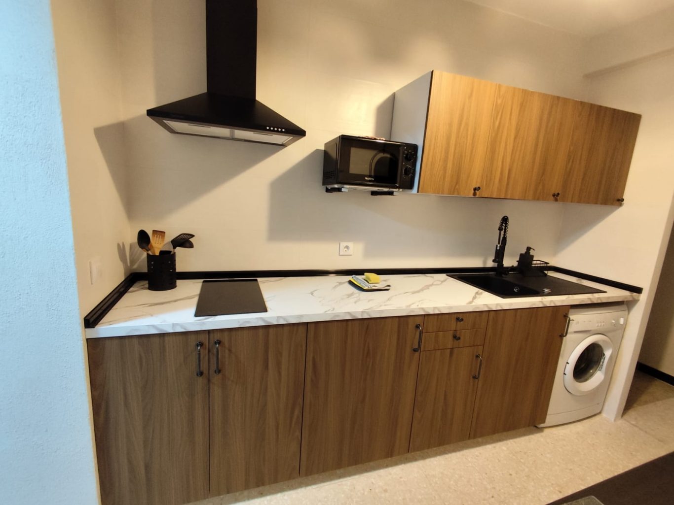 Cocina Cocina moderna con muebles de madera, encimera blanca y electrodomésticos.