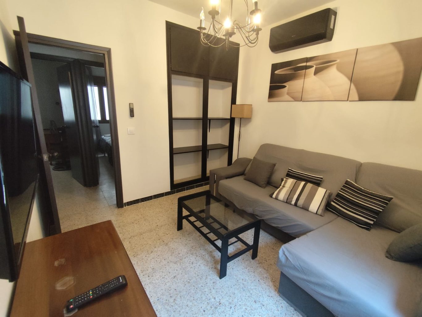 Salón Vista secundaria del salón con sofa, mesa de centro y mueble de TV, lampara de pie y baldas.